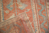 The machine-bound edge and flat-woven foundation of a distressed red and blue Oushak rug.