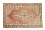 Vintage distressed Oushak rug with a geometric diamond medallion in faded cherry red, beige, and charcoal.