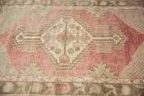 Sun-faded cherry red pile and central geometric medallion of a distressed Turkish Oushak rug.