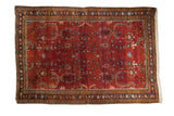 Vintage Sarouk rug featuring sprawling floral vines on a burgundy red field with noticeable abrash.