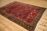 Vintage Sarouk rug from an angle, displaying color abrash over the burgundy floral field.