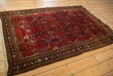Angled view of a vintage Sarouk rug highlighting the deep burgundy field and heavy color abrash.