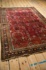 Angled view of a vintage Sarouk rug highlighting the heavy abrashes across the burgundy floral field.