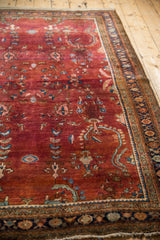 Angled view of a vintage Sarouk rug's heavy abrash and detailed navy floral border.