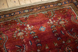 Vintage Sarouk rug corner with time-softened pile, heavy burgundy abrash, and a detailed navy border.