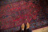 An antique Sarouk rug's raspberry red field featuring perched birds amid floral sprays, viewed from above.