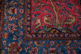 Corner detail of an antique Sarouk showing perched birds next to the intricate indigo floral border.