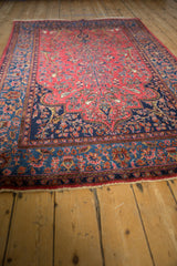 Low-angle view across the antique Sarouk rug, highlighting its lustrous wool pile and raspberry red field.