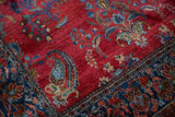 A large paisley boteh in sapphire and powder blue on the antique rug's red ground.