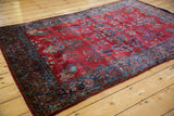 Low angle of an antique Kashan rug's short pile, pomegranate red field, and detailed paisley botehs.