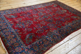 Angled view of an antique Kashan rug showing its gem-toned floral and paisley boteh pattern.