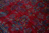 Sapphire blue paisley boteh and floral bouquets on a pomegranate red field of a fine Kashan rug.