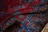 Draped view of an antique Kashan rug's dense pile with sapphire and ruby floral details.