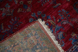 Corner view displaying the reverse weave and deep red floral pile of an antique Kashan rug.