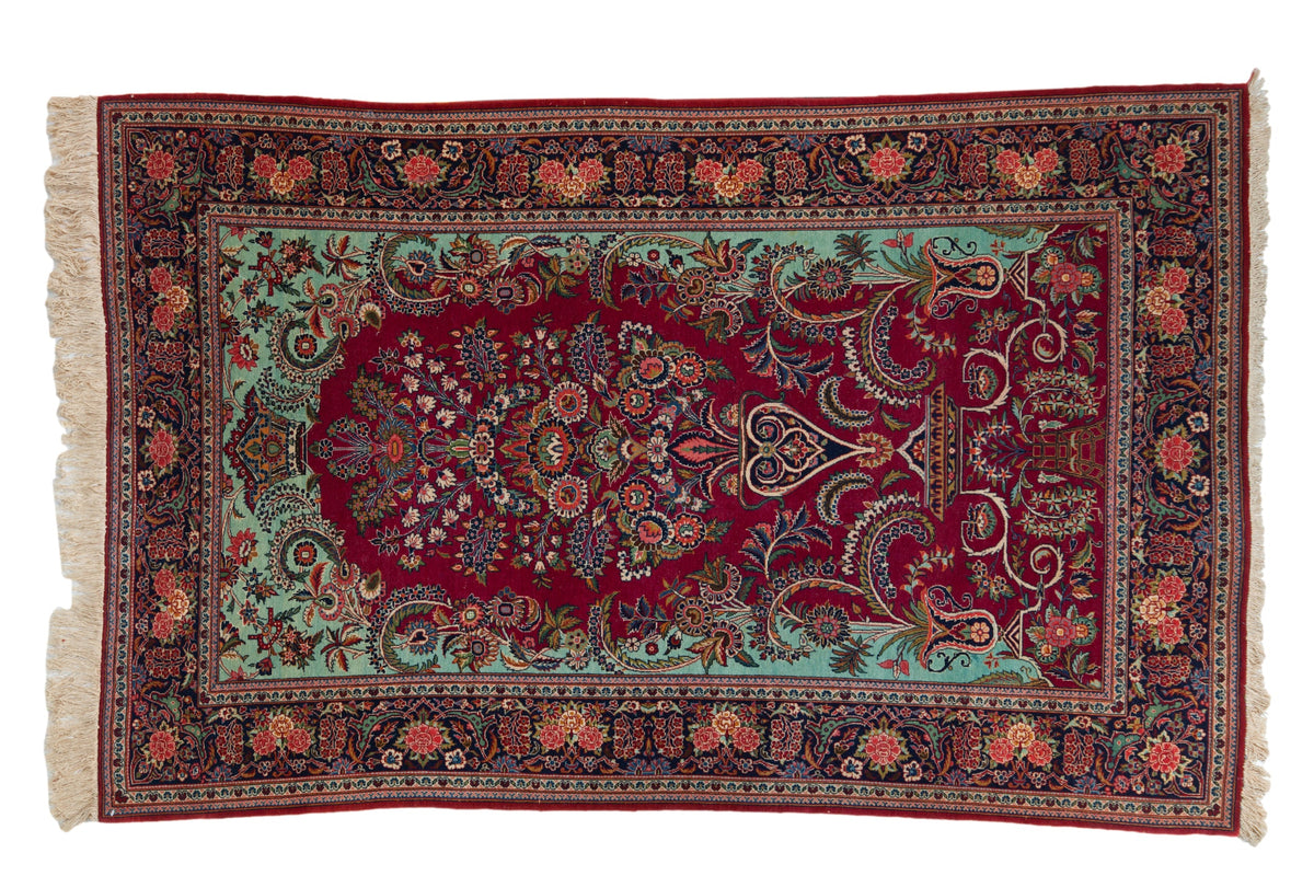 Vintage Dabir Kashan rug with a cherry red Tree of Life design, mint green spandrels, and a navy floral border.