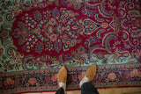 Overhead view showing the dense floral pattern of a vintage Dabir Kashan rug in cherry red and mint green.