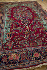 Angled view of a finely woven Dabir Kashan, with cherry red field and floral arabesques.
