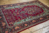 Angled perspective of a Dabir Kashan rug showing the cherry red floral field and mint green corners.