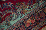 Finely woven rose clusters on the navy and mint green borders of a collector Persian Kashan.
