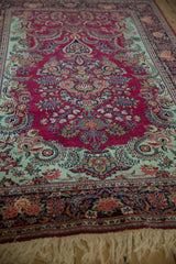 Angled view of a collector Dabir Kashan showing cherry red and mint green intricate blossoms.