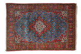 Vintage Persian Qom rug featuring a floral medallion on a sky blue field with geometric red borders.