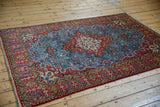 Full view of a vintage Persian Qom rug, highlighting its dense floral field and geometric borders.