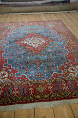 Perspective view of a vintage Persian Qom rug's classic sky blue and cherry red floral design.