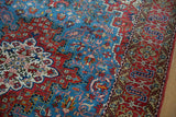 Detail of the angular geometric borders and floral vine scrolls in cherry red and sky blue on a Persian rug.