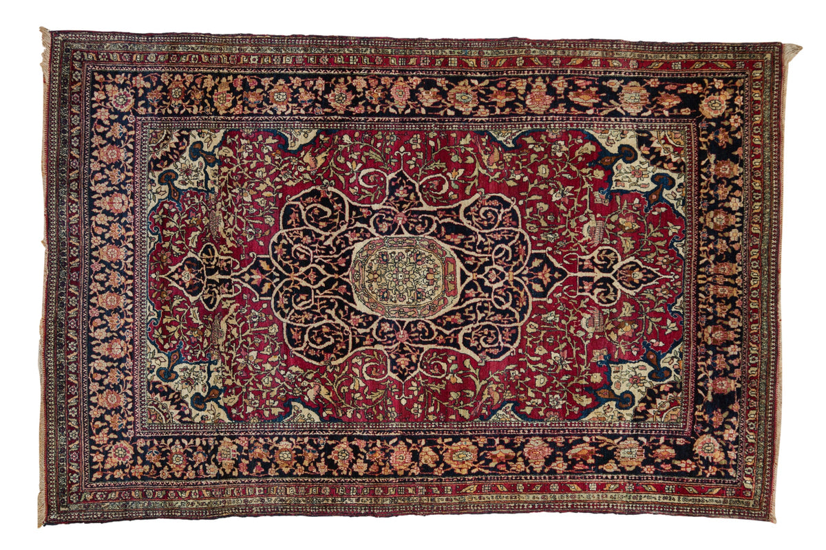 Antique Persian Isfahan rug with a central floral medallion, ivory spandrels, and a deep cochineal red field.