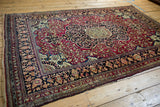 Radiating medallion and floral arabesques of a fine antique Isfahan rug in cochineal red and navy.