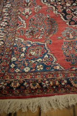 Corner of a vintage Sarouk rug detailing the vivid blue spandrel and ivory fringe.