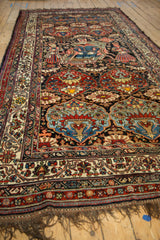 Angled view of an antique Afshar runner showing its pictorial tableau and Bakhtiari-style floral medallions.