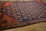 Antique Malayer rug's tomato red geometric floral main border with visible edge wear.