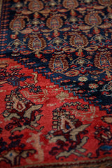 Antique Malayer rug's hand-knotted pile with navy, red, and sand boteh motifs.