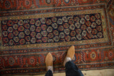 Navy geometric boteh field meeting brick red floral borders on an Antique Kurdish Hamadan rug.