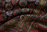 Hand-knotted pile texture featuring geometric boteh motifs in navy blue and brick red.