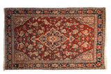 Vintage Persian Sarouk rug with a shield-like medallion on a cherry red field of floral botehs.
