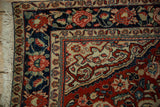 Detail of a vintage Sarouk rug's floral and vine border in navy blue, red, and ivory.