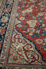 Angled detail of a vintage Sarouk rug showing the cherry red floral field beside its navy border.