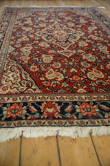 Low perspective along the vintage Sarouk rug's side, showing the short pile and dense floral boteh pattern.