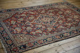 Vintage Sarouk rug with a cherry red field and navy border, shown from a full-length angle.