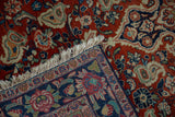 A vintage Persian Sarouk's corner folded to reveal its hand-knotted foundation and ivory fringe.