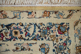 Corner of a vintage Kashan showing the saffron border, finely knotted blue vines, and ivory fringe.