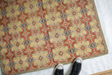 Overhead view of an antique Persian textile showing its scale and detailed botanical pattern.