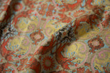 Shimmering silver threads highlight the intricate terracotta and blue botanical weave of the antique textile.
