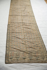 High-angle view of an 18th-century Persian brocade sash with floral stripes and poppy motifs.
