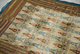 Corner of an antique Persian textile, showing the multi-striped border and blue fabric backing.