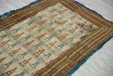 Angled view of an antique Persian textile highlighting its warm, earthy-toned striped border and blue backing.