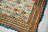 Corner of a Persian velvet textile showing the striped, earth-toned border and blue backing.