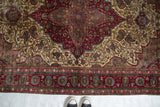 Floral palmettes in the burgundy border of a finely woven antique Mohtashem Kashan rug.